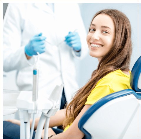 Young woman in yellow shirt smiling while sitting in dental chair