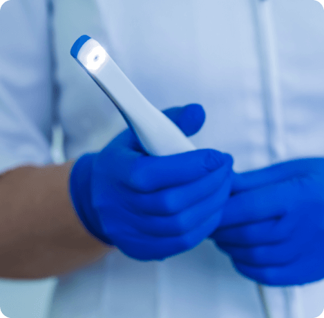Two gloved hands holding a thin white intraoral camera