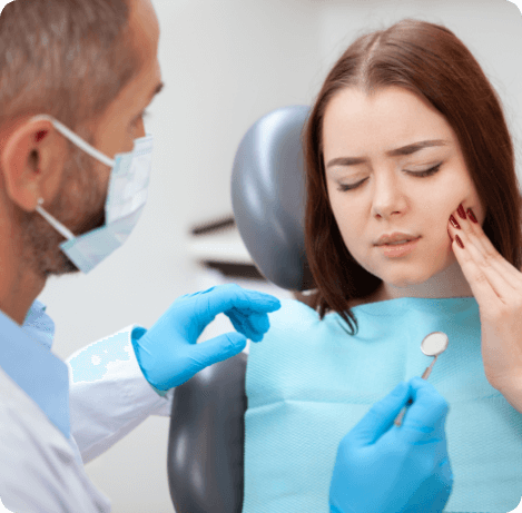 Woman in dental chair holding her cheek in pain