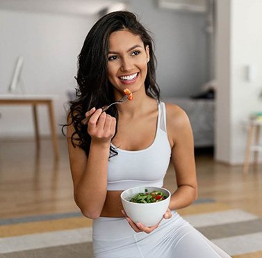 Woman smiling while eating salad at home