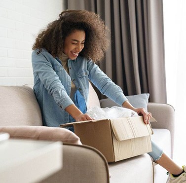 Woman smiling while opening package on couch