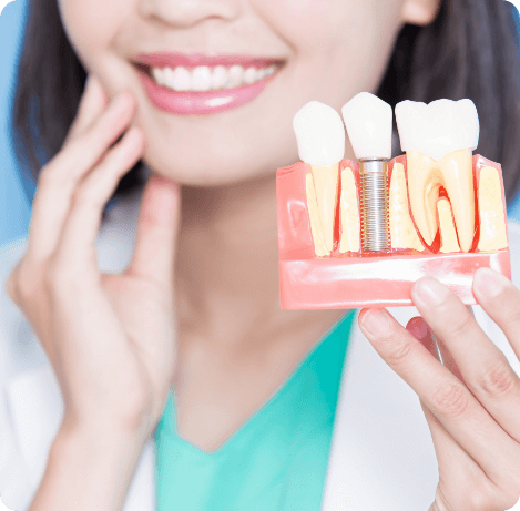 Dentist touching their cheek while holding a dental implant model