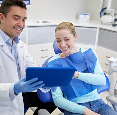 Patient and dentist smiling while looking at tablet