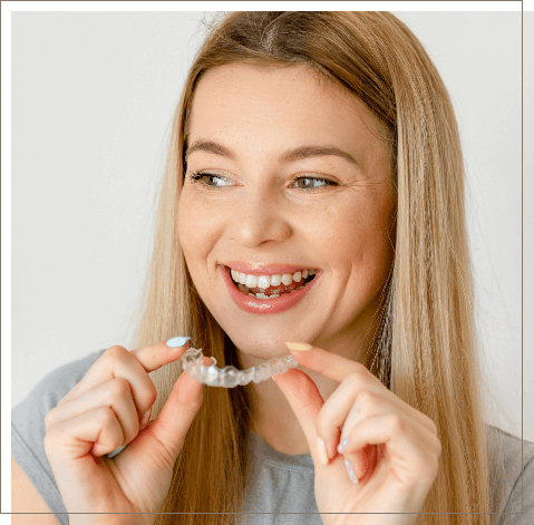 Smiling woman hooding Invisalign clear aligner in Oklahoma City