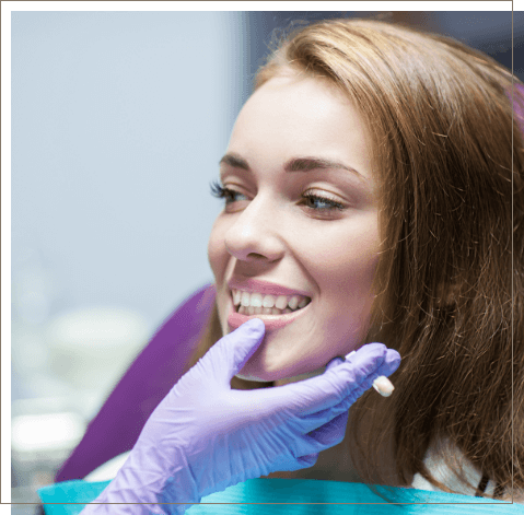 Dentist examining young woman's smile after restorative dentistry in Oklahoma City